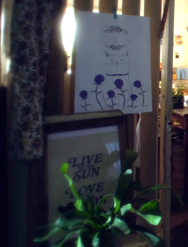 A cat poster and a sign that says 'Live by the Sun, Love by the Moon.'